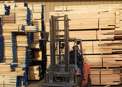 A forklift operator prepares to move a stack of lumber.